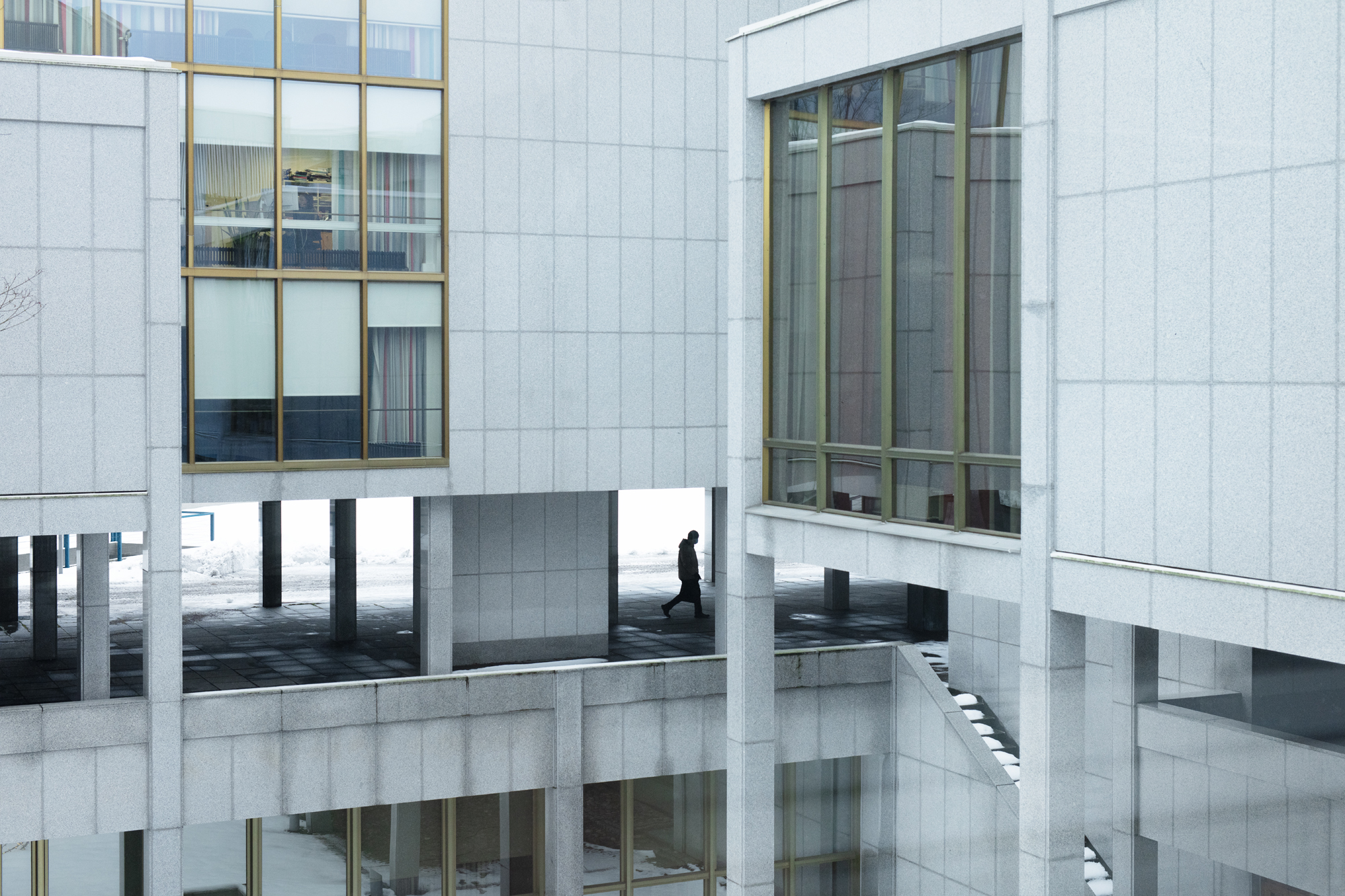 Illustration, grå kontorsbyggnaden och en man som går mellan kolonner.