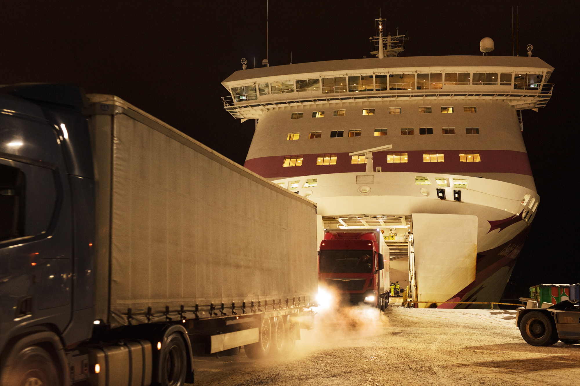 Illustration, a ship's bow and trucks at night time.