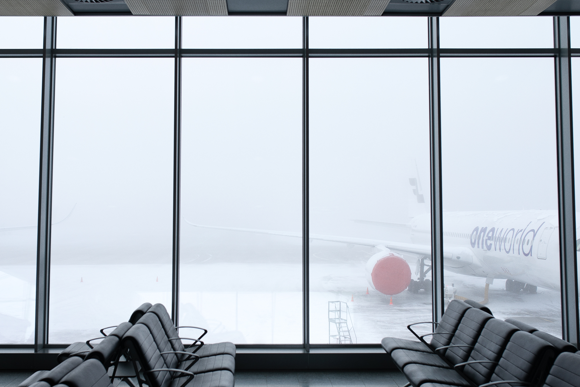 Illustration, benches at an airport and an airplane wing behind the window.